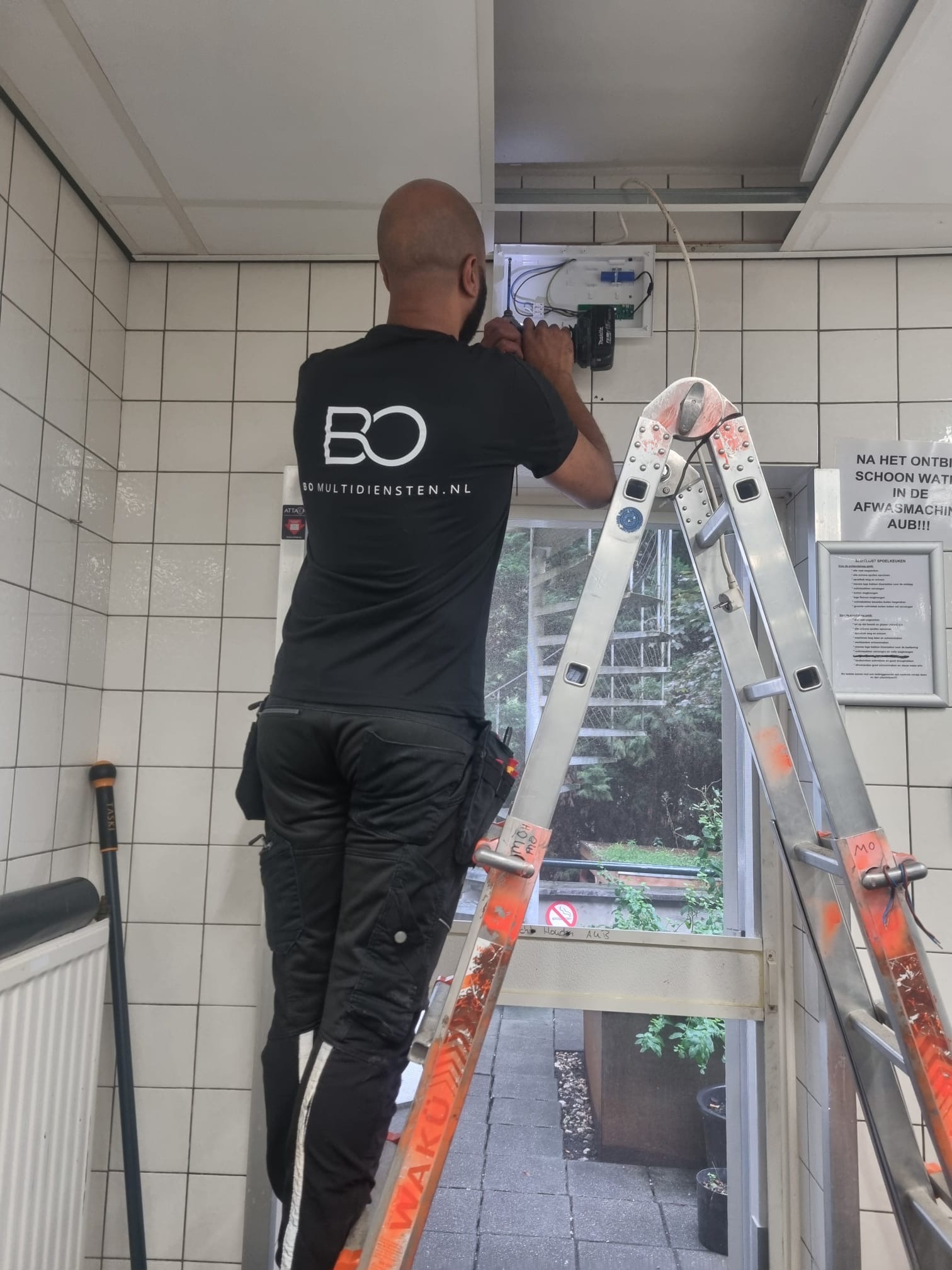 Monteur van BO Multidiensten aan het werk op een ladder
